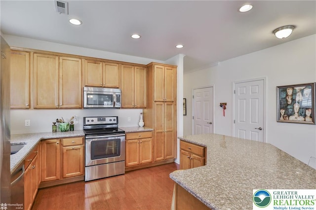2605 Victory Way, Hanover Twp, PA 18017 - kitchen featuring appliances with stainless steel finishes, wood finished floors, recessed lighting, light stone counters, and a center island