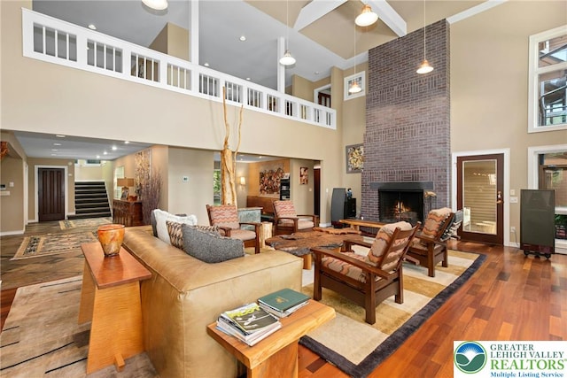 310 Hunters Farm Rd, Paradise Twp, PA 18332 - living area with a towering ceiling, stairs, wood finished floors, a brick fireplace, and baseboards