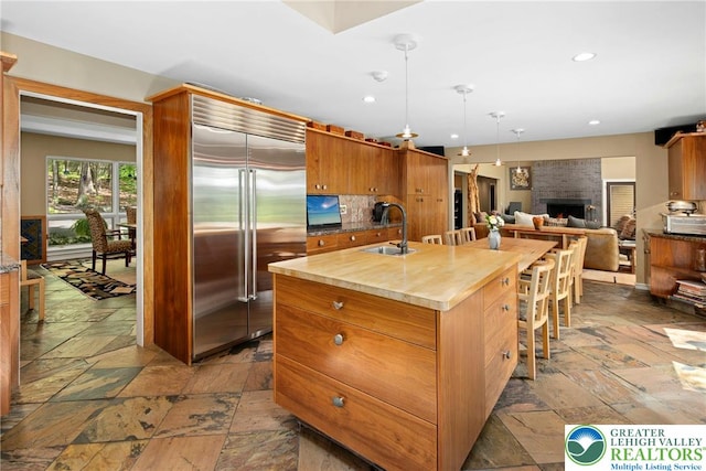 310 Hunters Farm Rd, Paradise Twp, PA 18332 - kitchen with stainless steel built in fridge, a sink, stone tile floors, recessed lighting, and a center island with sink