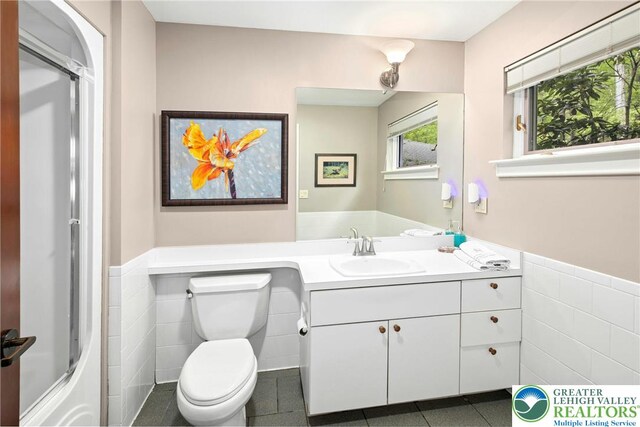 310 Hunters Farm Rd, Paradise Twp, PA 18332 - bathroom featuring tile walls, a wainscoted wall, toilet, an enclosed shower, and vanity