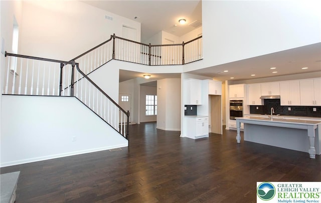 1350 Lorton Dr Unit 56, Forks Twp, PA 18040 - unfurnished living room featuring a sink, dark wood-type flooring, stairway, baseboards, and a high ceiling