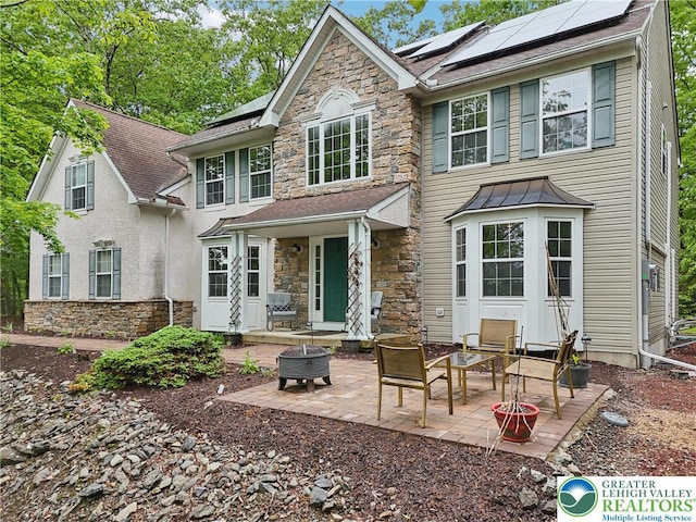 136 Outlook Ct, Middle Smithfield Twp, PA 18302 - back of house featuring stone siding, solar panels, a patio area, and a fire pit