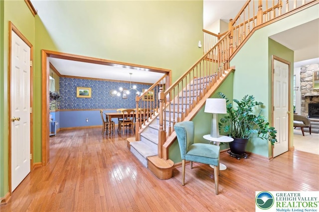 136 Outlook Ct, Middle Smithfield Twp, PA 18302 - stairs with wallpapered walls, hardwood / wood-style flooring, a chandelier, baseboards, and a stone fireplace