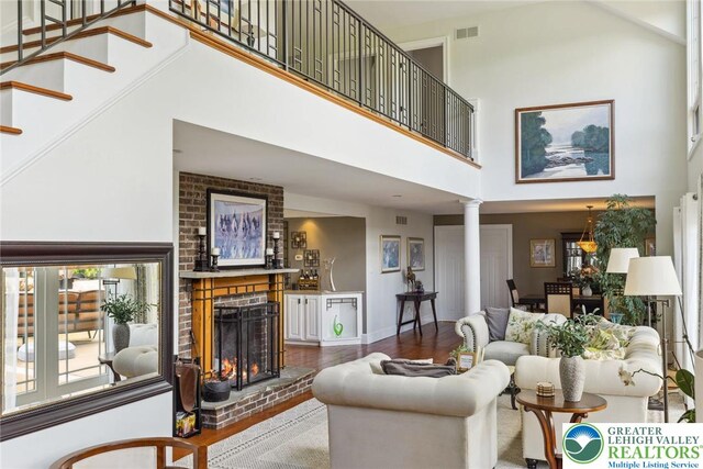 2965 Adams Way, Springfield Twp, PA 18077 - living area featuring a high ceiling, decorative columns, wood finished floors, a brick fireplace, and stairway