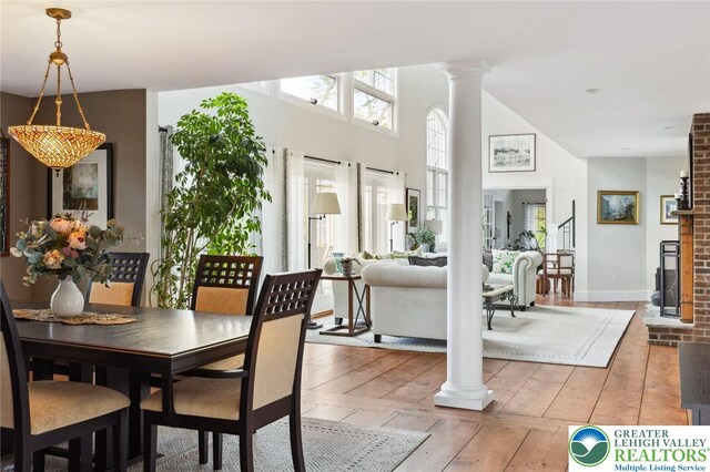 2965 Adams Way, Springfield Twp, PA 18077 - dining space with decorative columns, light wood-style floors, a fireplace, and a high ceiling