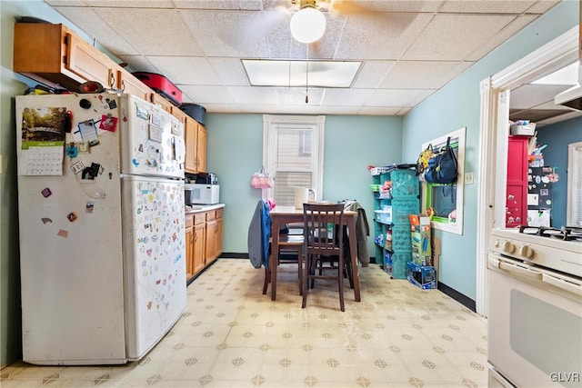 117 S 15th St, Wilson Borough, PA 18042 - kitchen featuring white appliances, light floors, a paneled ceiling, brown cabinetry, and baseboards