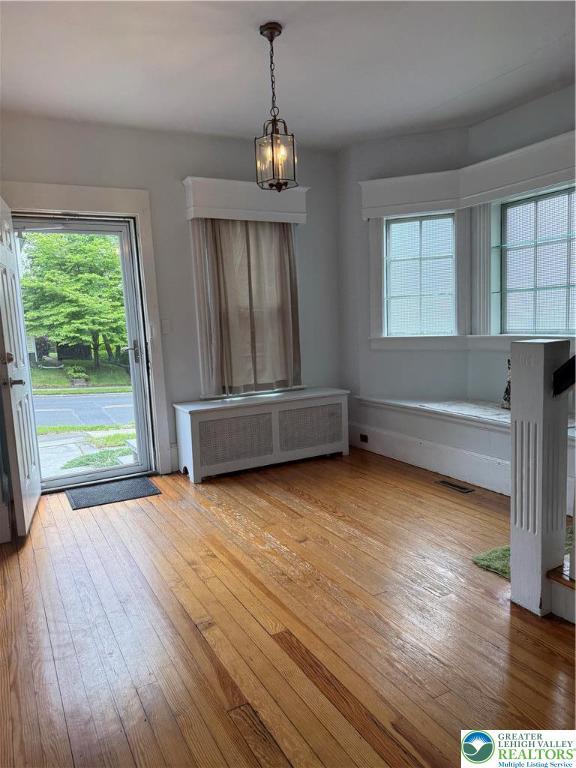 204 Analomink St, East Stroudsburg, PA 18301 - unfurnished dining area featuring radiator heating unit, hardwood / wood-style flooring, and a chandelier