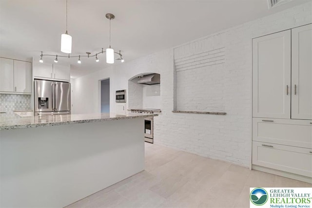 711 E Center St, Nesquehoning Borough, PA 18240 - kitchen with appliances with stainless steel finishes, brick wall, light stone countertops, white cabinets, and tasteful backsplash