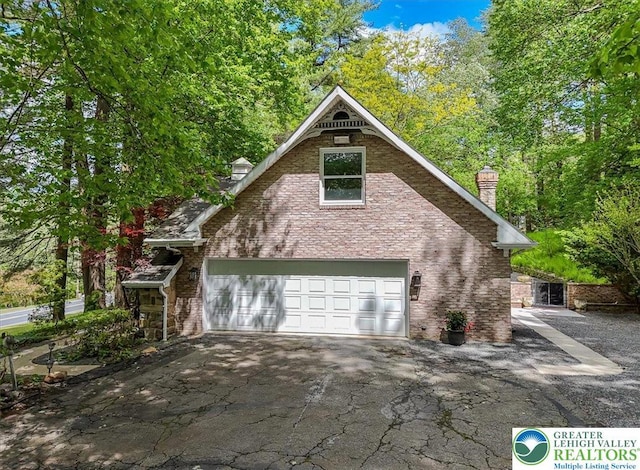 711 E Center St, Nesquehoning Borough, PA 18240 - view of home's exterior featuring a chimney, asphalt driveway, an attached garage, and brick siding