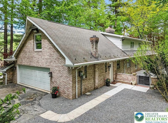 711 E Center St, Nesquehoning Borough, PA 18240 - view of front facade featuring a chimney, a garage, a shingled roof, driveway, and a gate