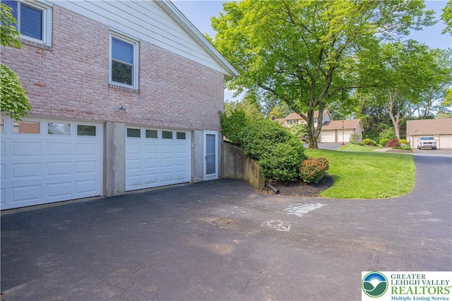 1131 28th St, Allentown City, PA 18104 - view of side of property featuring brick siding, asphalt driveway, an attached garage, and a yard