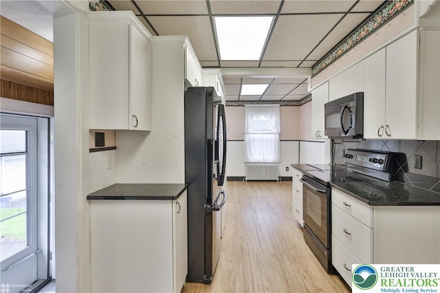 171 N New St, Nazareth Borough, PA 18064 - kitchen featuring black appliances, radiator heating unit, white cabinetry, light wood-style flooring, and tasteful backsplash