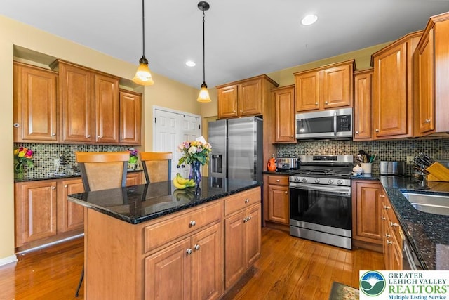 140 Birdie Way, Eldred Twp, PA 18058 - kitchen with stainless steel appliances, dark wood finished floors, a center island, brown cabinets, and decorative backsplash