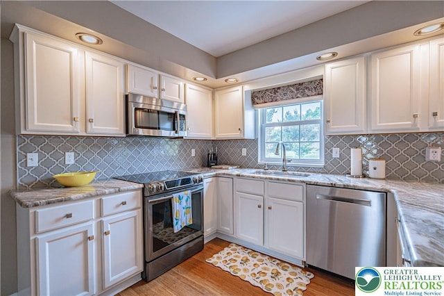 3624 Mcintosh Dr, North Whitehall Twp, PA 18069 - kitchen with stainless steel appliances, a sink, white cabinets, light wood-style flooring, and recessed lighting