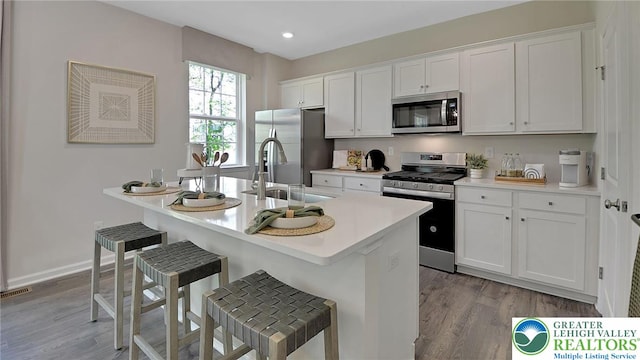 311 Knollwood Dr, Forks Twp, PA 18040 - kitchen with appliances with stainless steel finishes, a sink, light wood-style floors, white cabinetry, and a breakfast bar