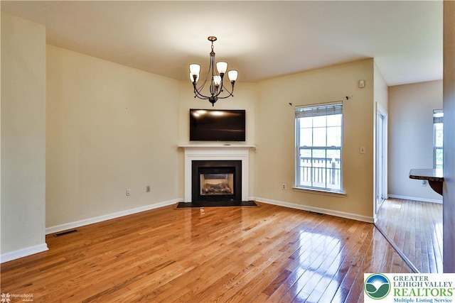27 Willow Dr, Palmer Twp, PA 18045 - unfurnished living room featuring a chandelier, light wood-style flooring, a fireplace with flush hearth, and baseboards