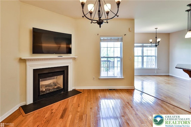 27 Willow Dr, Palmer Twp, PA 18045 - unfurnished living room featuring a chandelier, hardwood / wood-style floors, a glass covered fireplace, and baseboards