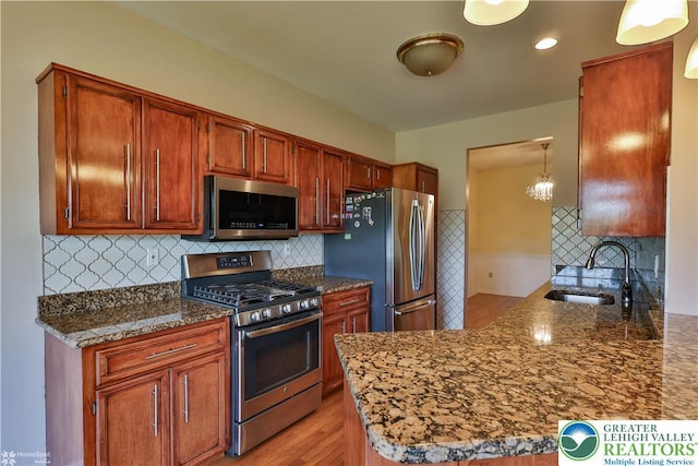 27 Willow Dr, Palmer Twp, PA 18045 - kitchen with stainless steel appliances, a sink, light wood-style flooring, brown cabinetry, and decorative backsplash