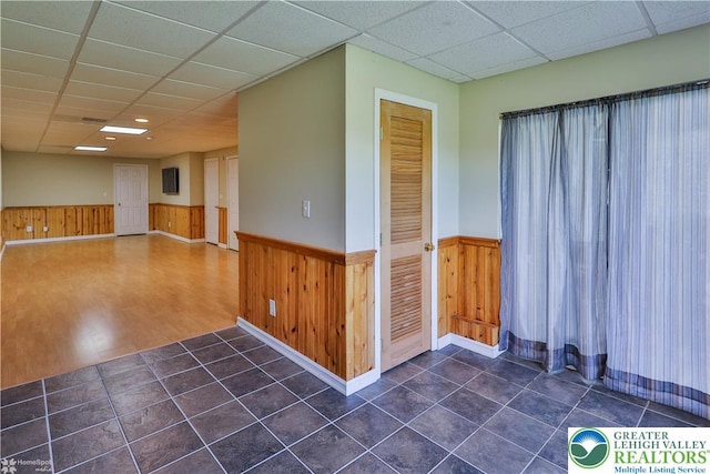 27 Willow Dr, Palmer Twp, PA 18045 - empty room with a wainscoted wall, a drop ceiling, dark tile patterned flooring, wood walls, and baseboards