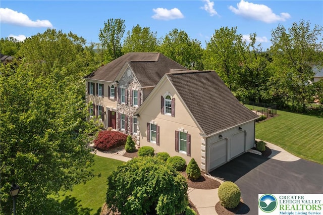 168 Forsythia Ln, Upper Macungie Twp, PA 18104 - view of front of house featuring stucco siding, asphalt driveway, a shingled roof, an attached garage, and a front lawn
