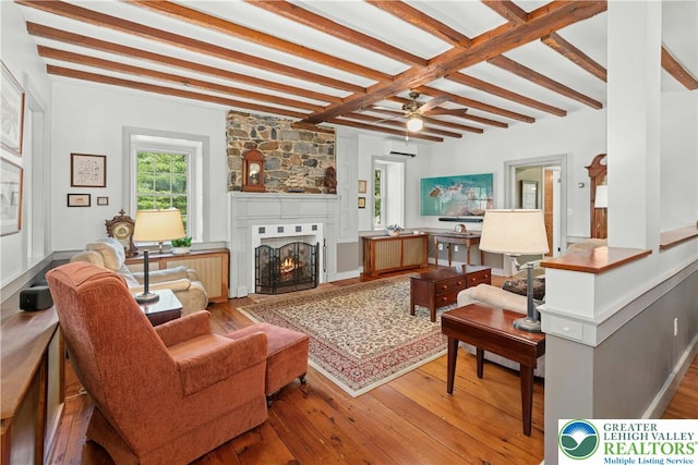 3139 Wilson Ave, Bethlehem Twp, PA 18020 - living room with beamed ceiling, hardwood / wood-style floors, a large fireplace, a wall unit AC, and a ceiling fan