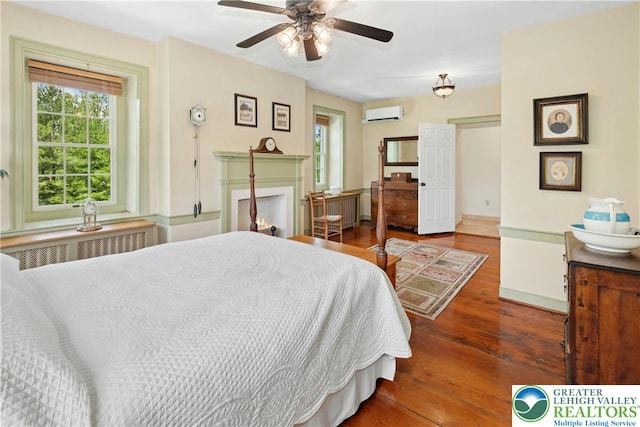 3139 Wilson Ave, Bethlehem Twp, PA 18020 - bedroom with a wall mounted AC, hardwood / wood-style floors, a lit fireplace, radiator, and a ceiling fan