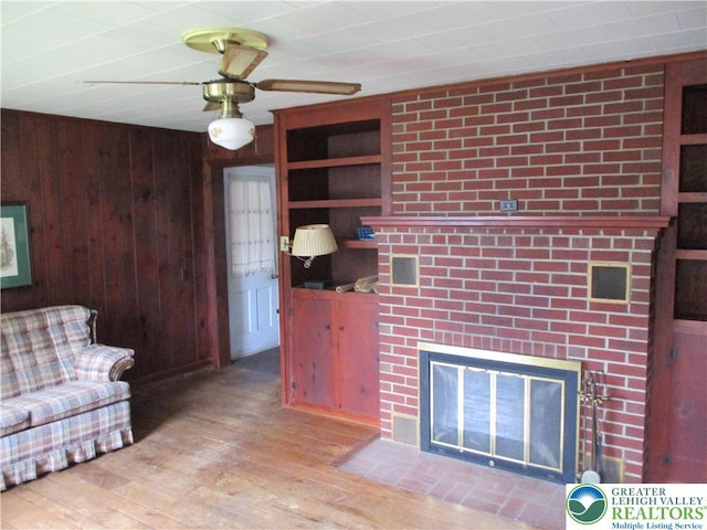 244 High St, Tatamy Borough, PA 18085 - living room with wood walls, ceiling fan, wood finished floors, and a fireplace