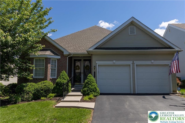 5054 Valley Stream Ln, Lower Macungie Twp, PA 18062 - view of front facade featuring french doors, a garage, driveway, brick siding, and roof with shingles