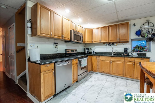 2107 3rd St, Bethlehem Twp, PA 18020 - kitchen with appliances with stainless steel finishes, a sink, a paneled ceiling, brown cabinets, and light marble finish floors