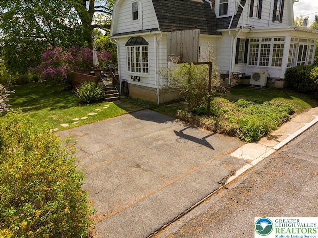 215 S 22nd St, Allentown City, PA 18104 - view of front facade with a wooden deck, a shingled roof, a gambrel roof, a cooling unit, and a front lawn