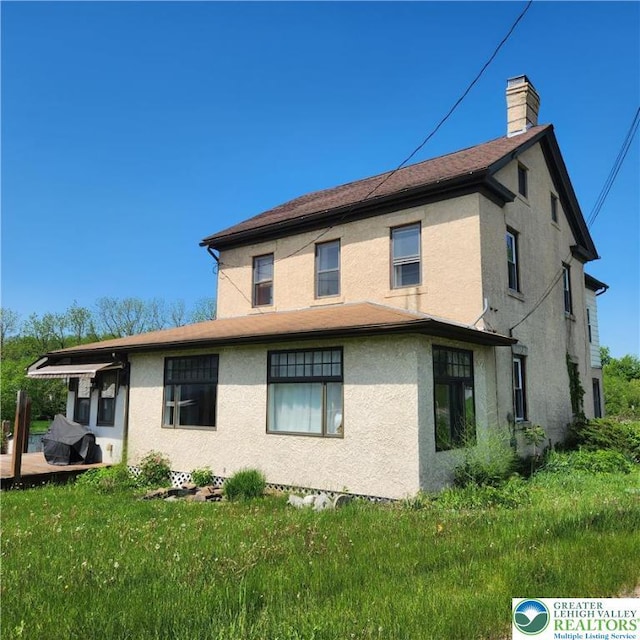 2357 Spring St, North Whitehall Twp, PA 18037 - back of property with stucco siding, a chimney, and a yard