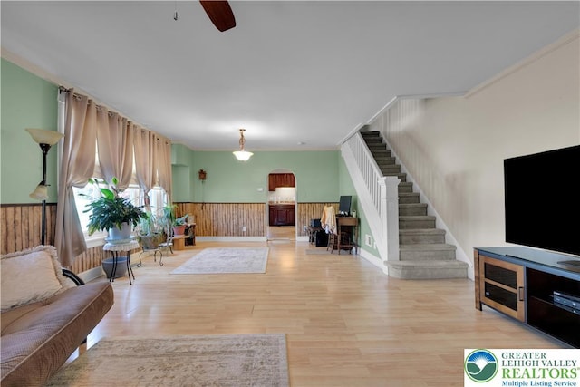 622 Scholl Ave, Salisbury Twp, PA 18015 - living room featuring arched walkways, stairway, wainscoting, light wood-type flooring, and a ceiling fan