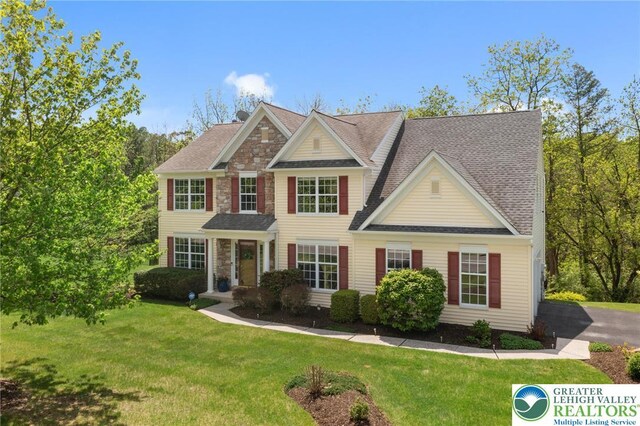 2238 Oakwood Ct, Lowhill Twp, PA 18051 - view of front facade with a front yard, stone siding, and roof with shingles