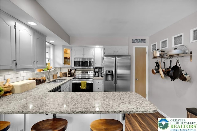 5401 Hale Ave, Hanover Twp, PA 18017 - kitchen with appliances with stainless steel finishes, a peninsula, a sink, dark wood-style flooring, and decorative backsplash
