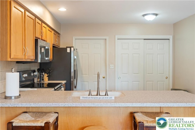 2630 Lower Way, Forks Twp, PA 18040 - kitchen with black range with electric cooktop, stainless steel microwave, a sink, a breakfast bar area, and tasteful backsplash