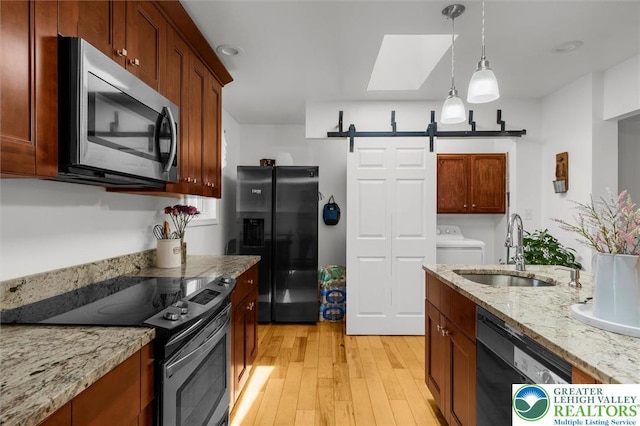 3079 Eldridge Ave, Palmer Twp, PA 18045 - kitchen with black appliances, a sink, a barn door, light wood finished floors, and washer / dryer