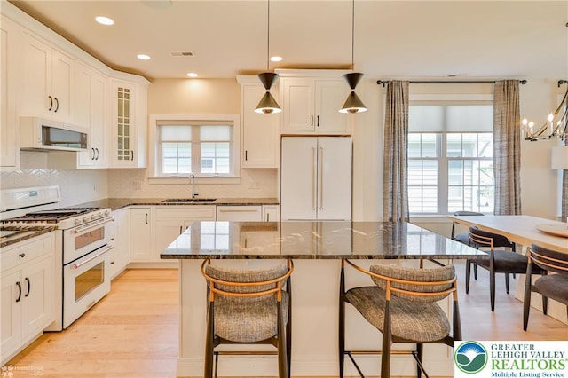 3896 Independence Dr, Easton, PA 18045 - kitchen featuring white appliances, a sink, dark stone countertops, a breakfast bar area, and backsplash