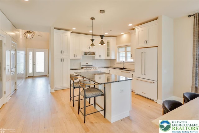 3896 Independence Dr, Easton, PA 18045 - kitchen with white appliances, a breakfast bar area, light wood-style floors, white cabinets, and a center island
