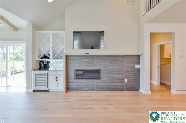 3896 Independence Dr, Easton, PA 18045 - unfurnished living room with wine cooler, bar, wood finished floors, baseboards, and a glass covered fireplace