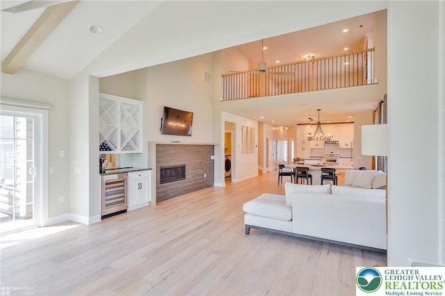 3896 Independence Dr, Easton, PA 18045 - living room featuring wine cooler, light wood finished floors, high vaulted ceiling, baseboards, and a glass covered fireplace