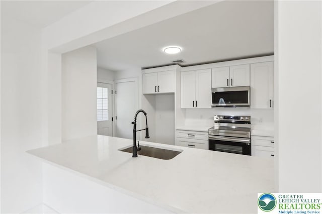 624 E 8th St, Northampton Borough, PA 18067 - kitchen featuring appliances with stainless steel finishes, a sink, a peninsula, and white cabinetry
