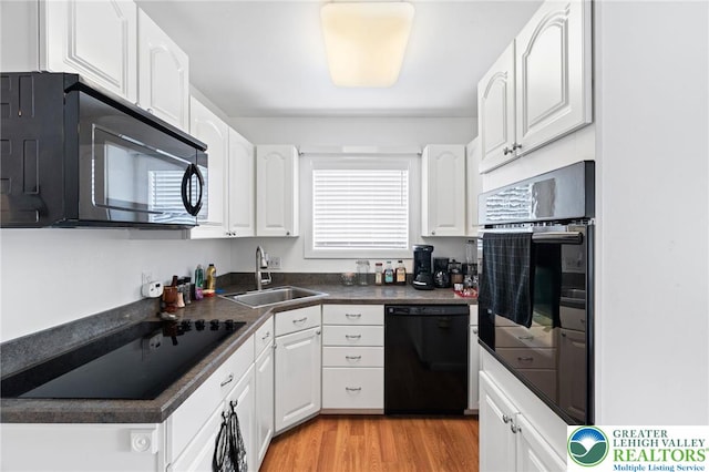 956 E Linden St, Allentown City, PA 18109 - kitchen featuring black appliances, a sink, dark countertops, white cabinets, and light wood-style flooring