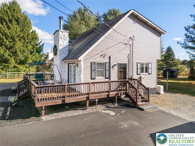 64 Autumn Ln, Penn Forest Twp, PA 18229 - back of property featuring a wooden deck, a shingled roof, and a chimney