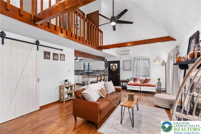 64 Autumn Ln, Penn Forest Twp, PA 18229 - living area with a ceiling fan, high vaulted ceiling, a wall mounted air conditioner, a barn door, and wood finished floors