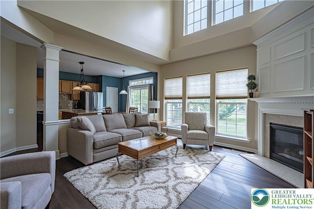 8592 Cascade Rd, Upper Macungie Twp, PA 18031 - living area with a premium fireplace, dark wood-style floors, ornate columns, a towering ceiling, and baseboards