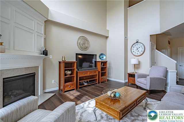 8592 Cascade Rd, Upper Macungie Twp, PA 18031 - living room featuring dark wood finished floors, baseboards, a towering ceiling, and a glass covered fireplace