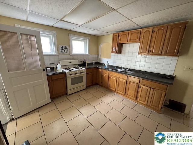 226 Adrain St, Emmaus Boro, PA 18049 - kitchen with white gas stove, dark countertops, a sink, brown cabinets, and a paneled ceiling