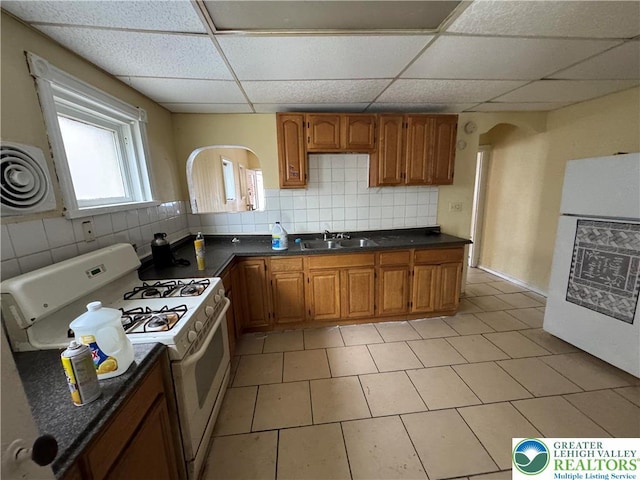 226 Adrain St, Emmaus Boro, PA 18049 - kitchen with white appliances, brown cabinetry, dark countertops, a paneled ceiling, and backsplash