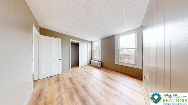 853 N Jordan St, Allentown City, PA 18102 - unfurnished bedroom featuring radiator, light wood finished floors, wood walls, a closet, and a paneled ceiling