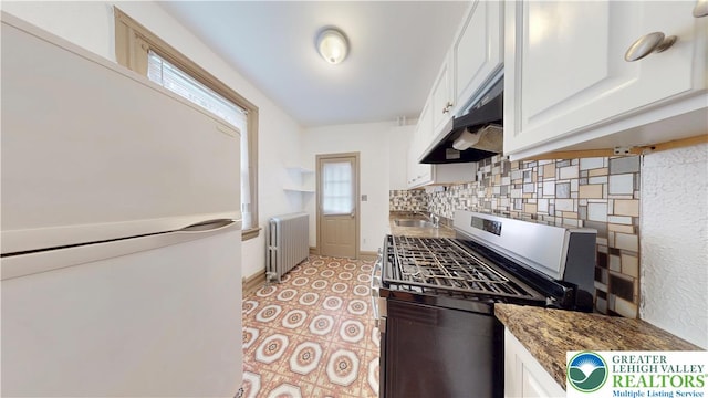 853 N Jordan St, Allentown City, PA 18102 - kitchen with radiator, freestanding refrigerator, gas range, white cabinets, and decorative backsplash
